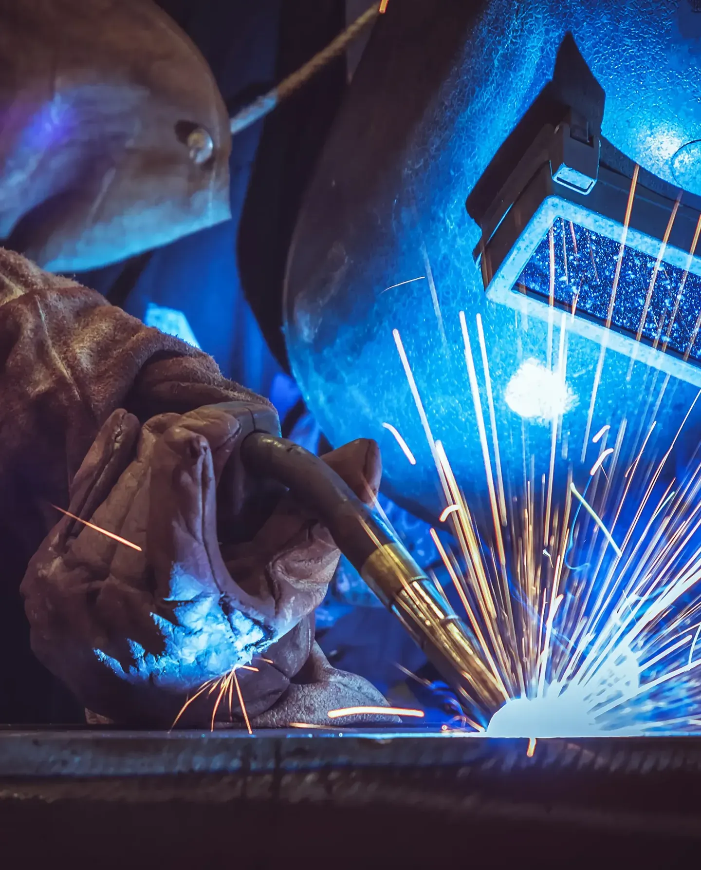 A close-up of a welder wearing a mask and protective gear.