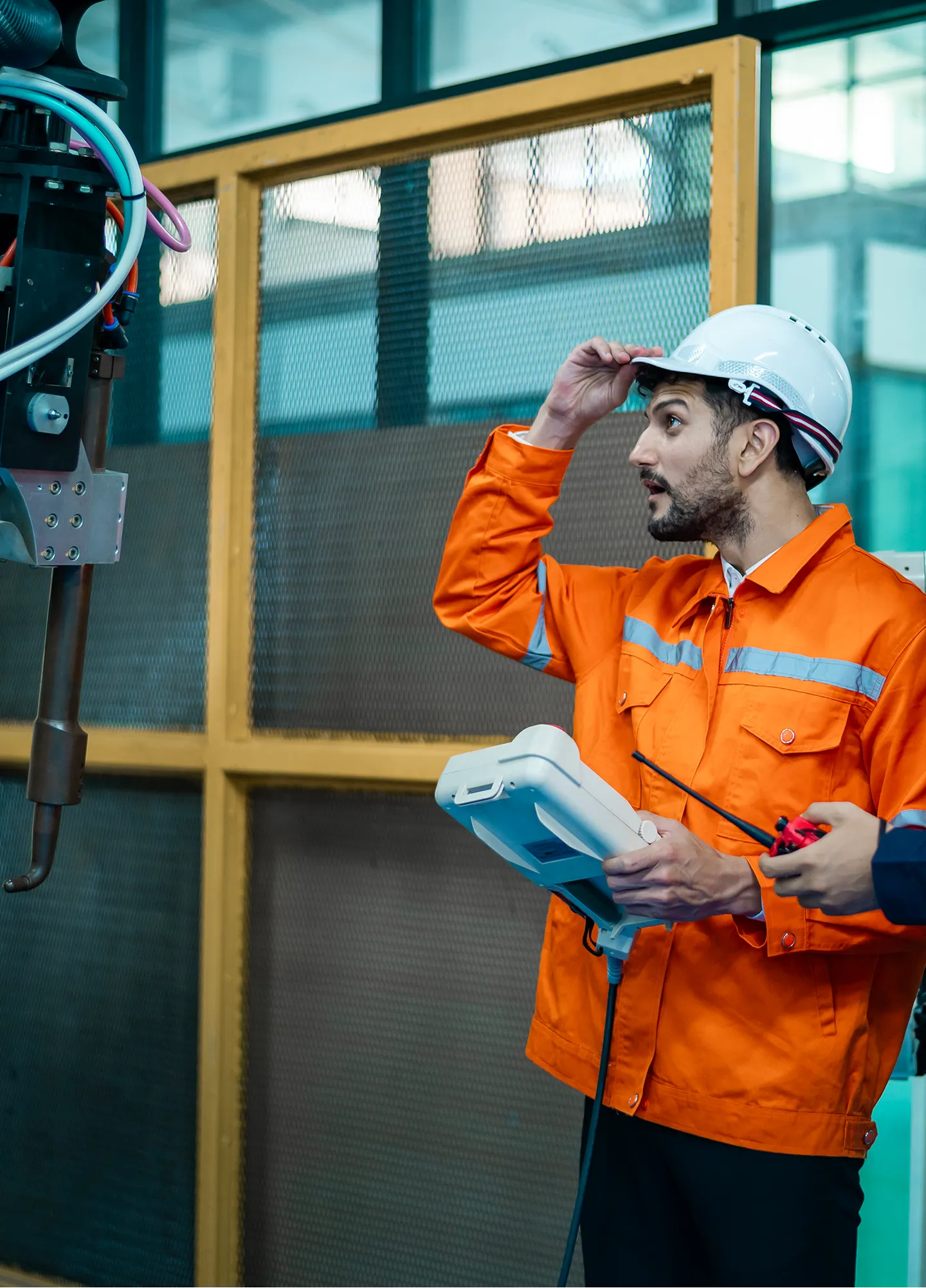 A technician in an orange uniform inspecting industrial machinery.