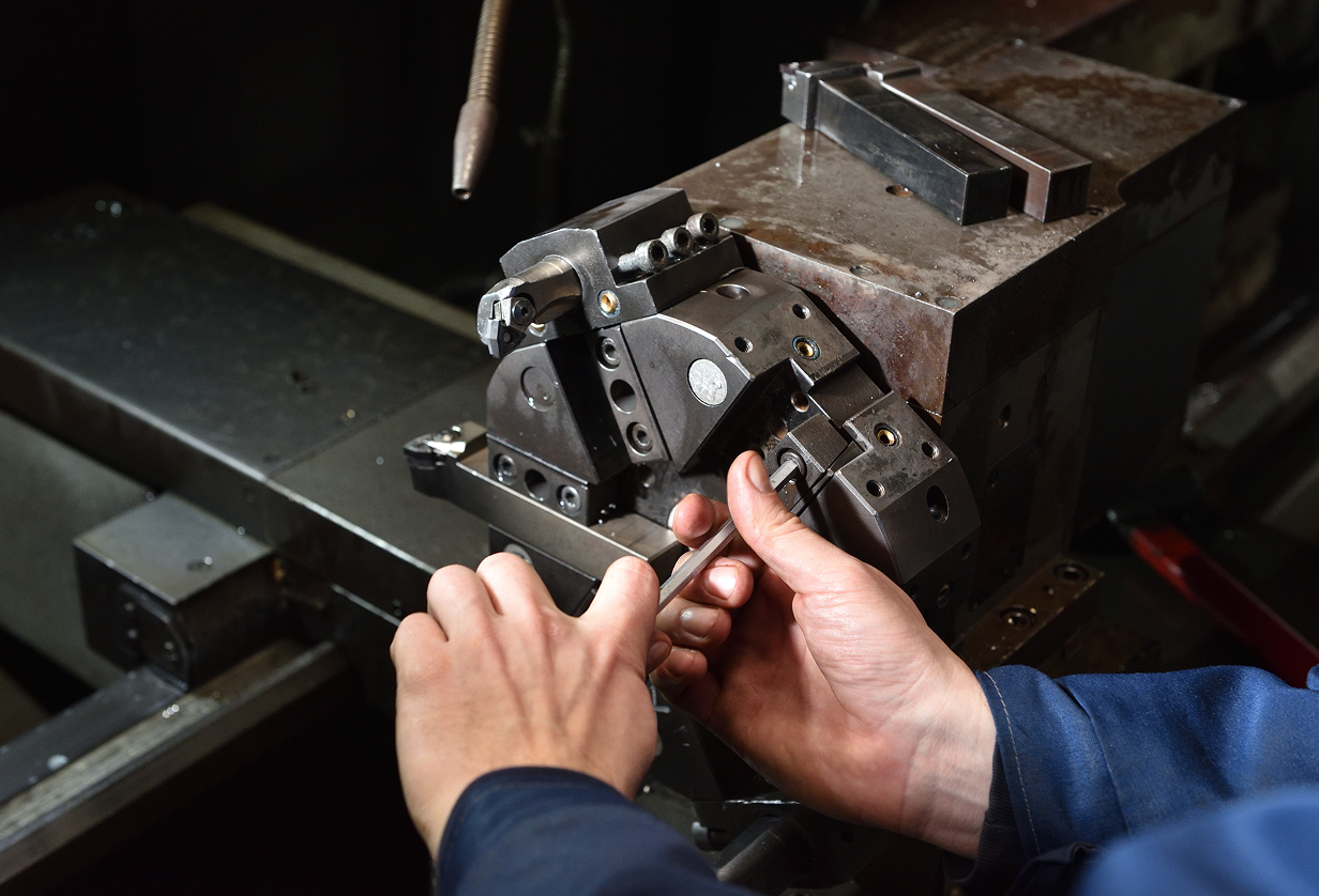 Hands using an Allen wrench to adjust machinery.