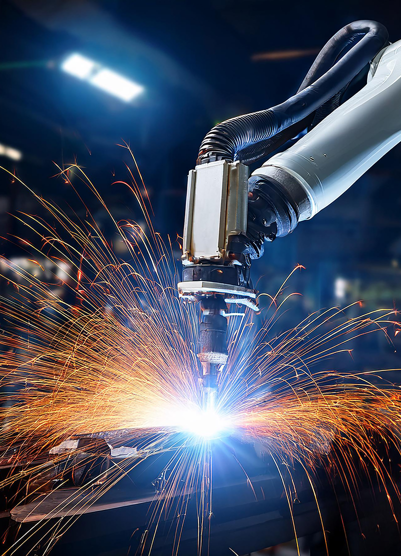 An automated robotic arm welding metal with bright sparks.